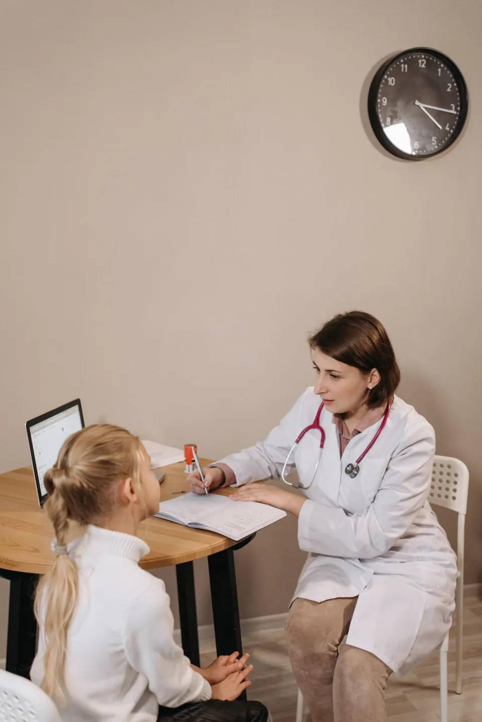 A pediatric clinician examining a child with a guardian present